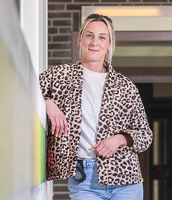 Vrouw leunt binnen, draagt luipaardjas en jeans blauw