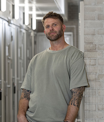 Persoon met tatoeages in gang met metalen deuren