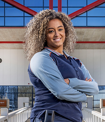 Vrouw in uniform staat glimlachend met armen gekruist