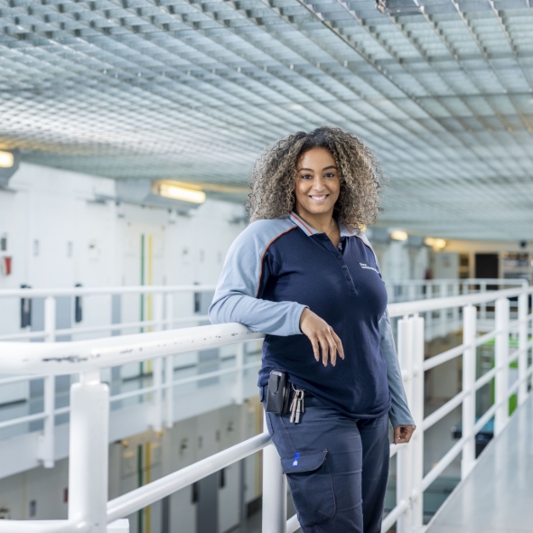 Vrouw in uniform leunt glimlachend aan reling