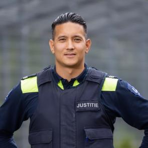Een man in uniform staat buiten en kijkt in de camera