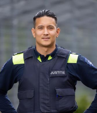 Een man in uniform staat buiten en kijkt in de camera