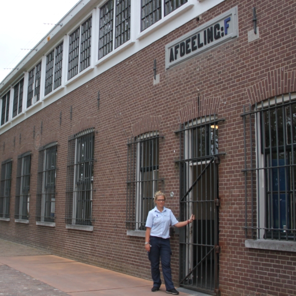 Medewerker staat bij gevangenisingang van bakstenen gebouw