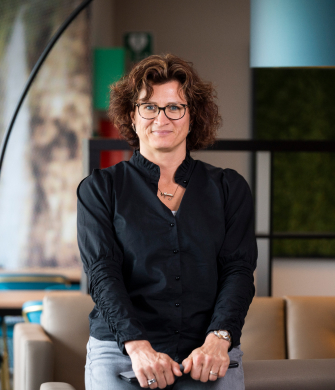product owner Judith, houdt een laptop vast en kijkt in de camera