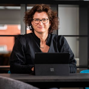 Persoon met bril achter laptop op kantoor