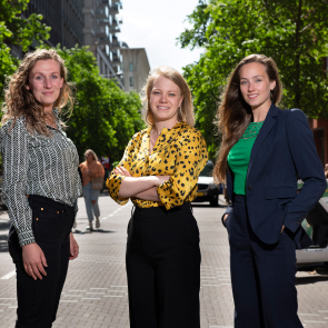 Drie personen poseren op zonnige stadsstraat