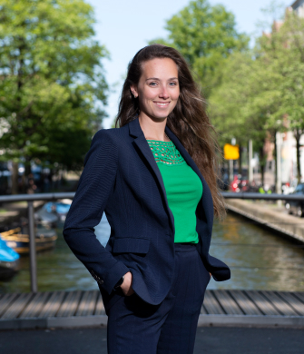 vrouw met bruine lange haren staat buiten en kijkt in de camera