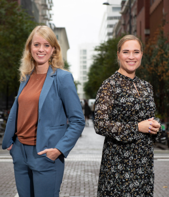 Twee vrouwen staan buiten en kijken in de camera