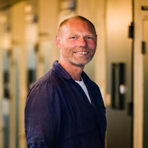 Een man staat in een gang van een kliniek en kijkt in de camera
