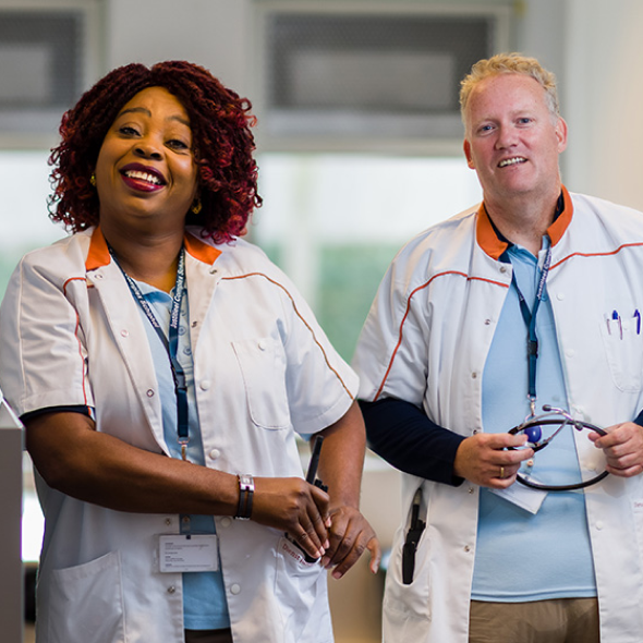 Twee zorgmedewerkers glimlachen in kliniek