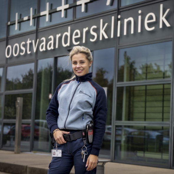 Vrouw in uniform staat voor modern gebouw met glasgevel