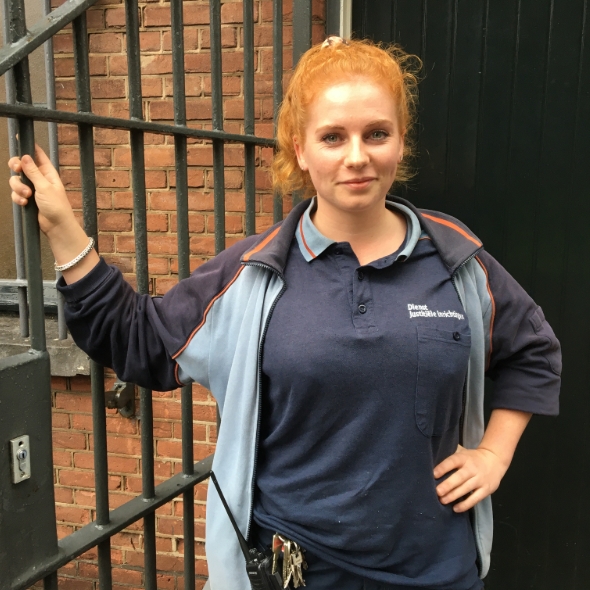 Vrouw in uniform staat bij gevangenispoort