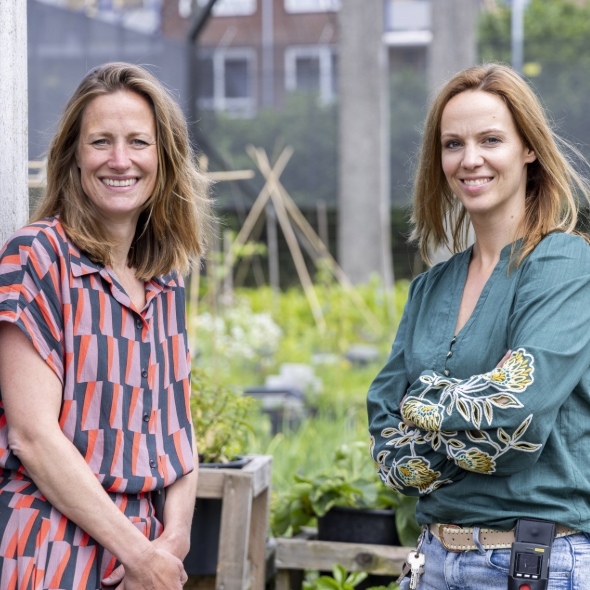 Twee lachende vrouwen staan in een stadstuin samen