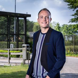 Een man staat buiten bij een kliniek en kijkt in de camera