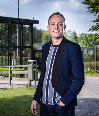 Een man staat buiten bij een kliniek en kijkt in de camera