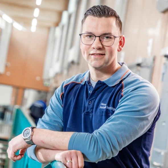 Medewerker leunt op reling in gevangenisgang