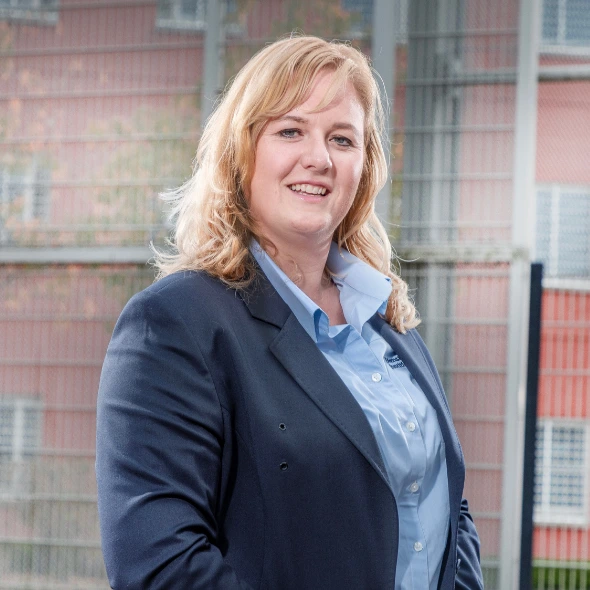 Persoon staat buiten bij gebouw met metalen hekwerk