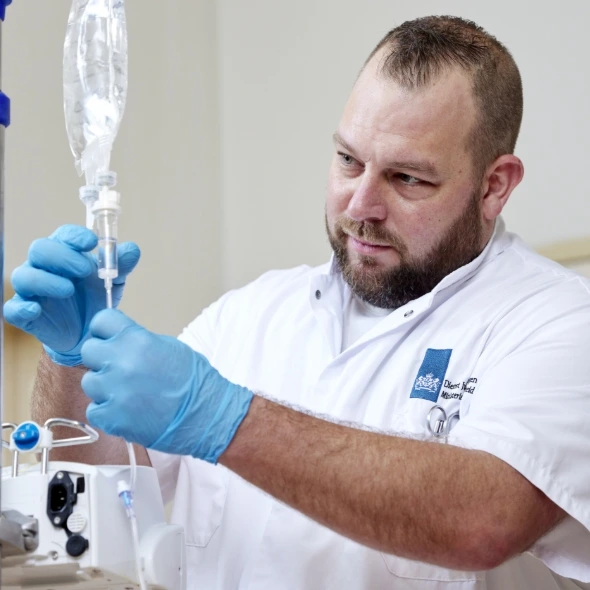 Medewerker stelt infuuszak in met blauwe handschoenen