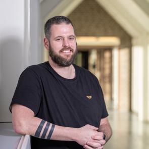 Een man staat buiten bij een kliniek en kijkt in de camera