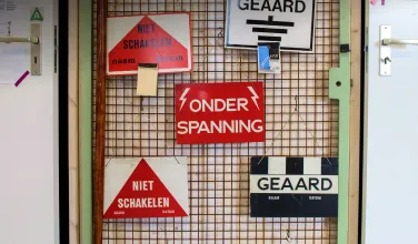 Electrical safety warning signs on a metal grid wall