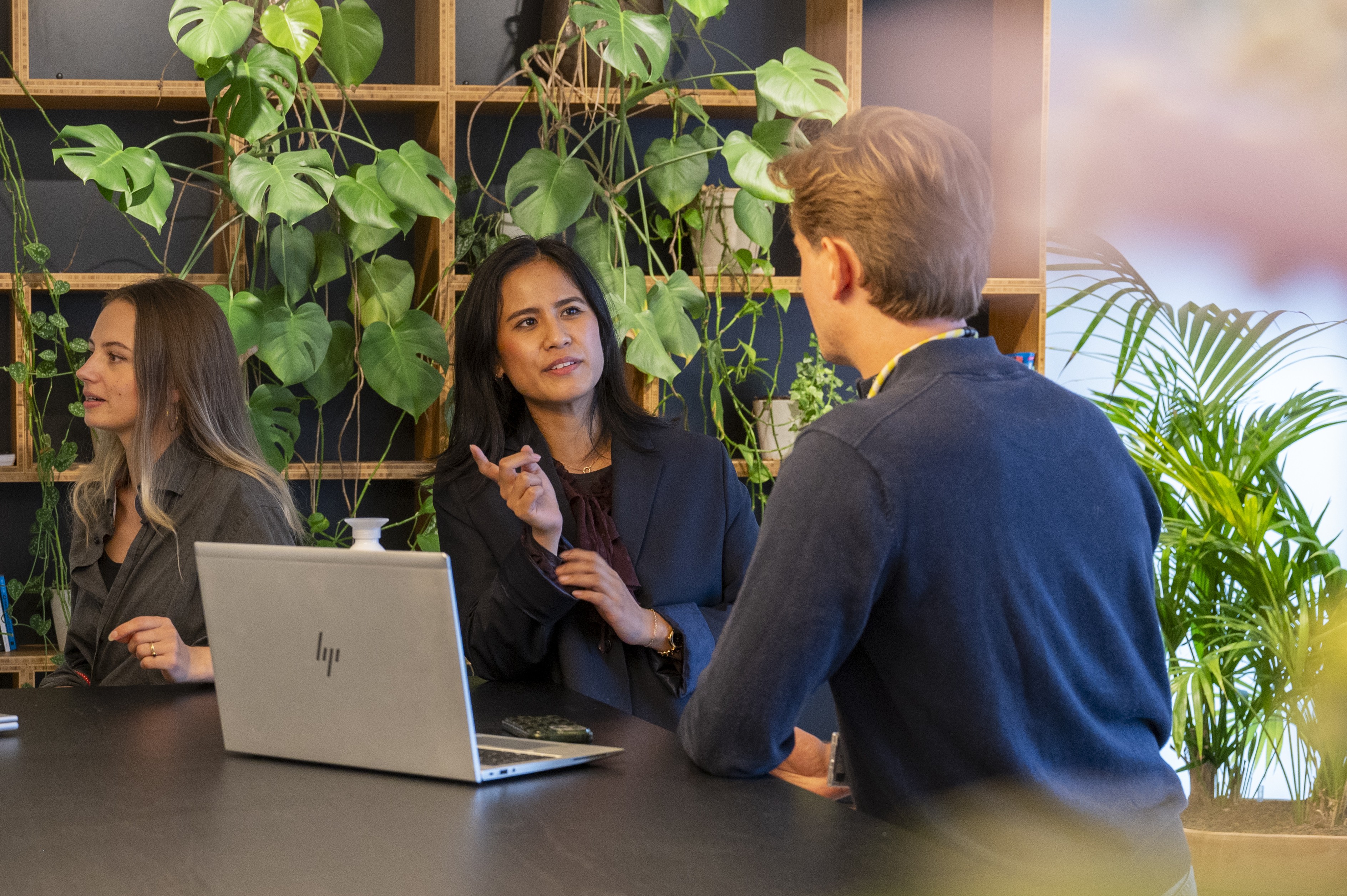 Two Stedin utility workers wearing safety helmets and high-visibility jackets inspect electrical panels inside a facility.