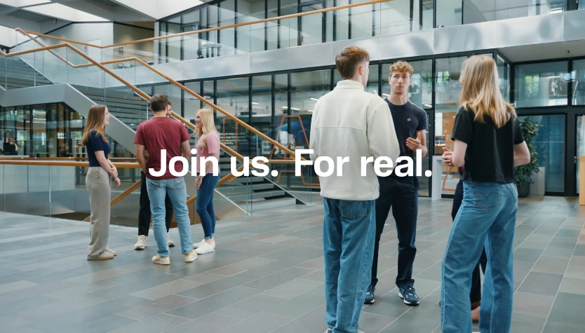 Group of employees talking in a modern office lobby.