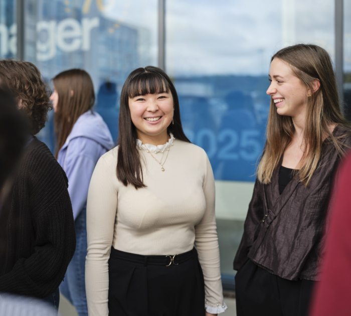 People standing and talking near a glass building.