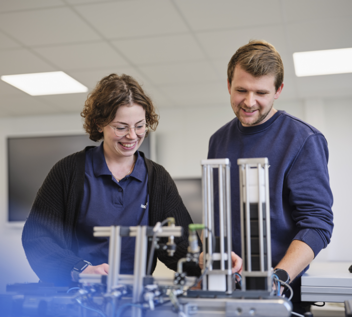 Employees working on a mechanical device in a lab.