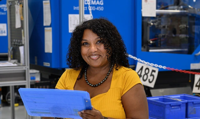 Smiling factory worker holding clipboard