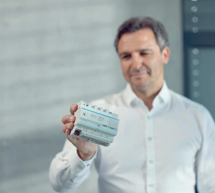 Man holding electronic control module indoors