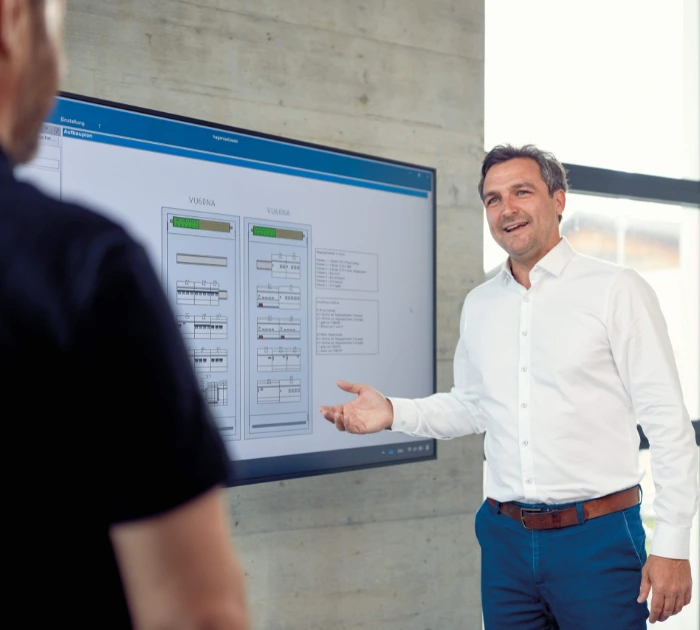 Man presenting information on large digital screen indoors