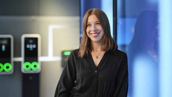 Smiling woman standing near glass wall in office