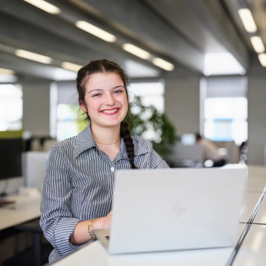 Lächelnde Frau arbeitet am Laptop im Büro