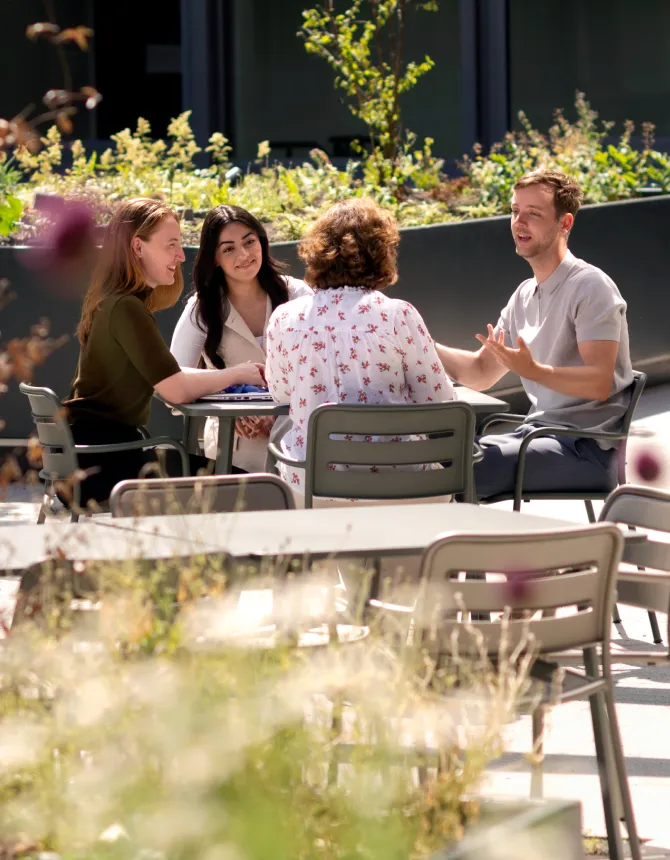 Colleagues chatting at outdoor tables in a green office courtyard