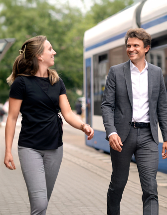 Twee collega’s lopen en praten bij tramhalte