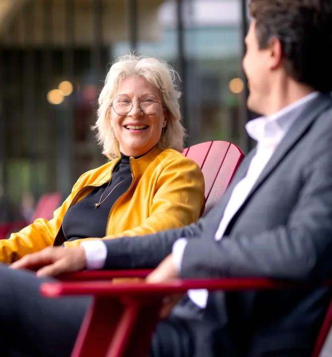 Lachende vrouw met bril in gesprek met een collega buiten