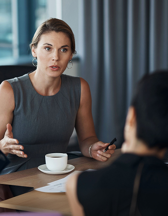 Zakenvrouw in gesprek aan tafel met koffie