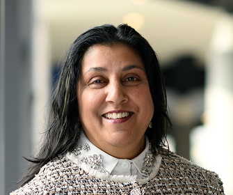 Woman with dark hair in jacket and white blouse