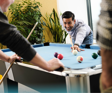 Personen spelen een potje poolbiljart in een kantoorruimte.
