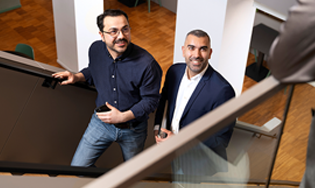 Twee personen lopen een trap op in een kantooromgeving.