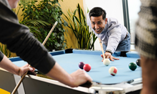 Personen spelen een potje poolbiljart in een kantoorruimte.