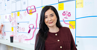 Persoon voor een bord met planningsoverzichten en roze juridische iconen eromheen.