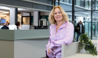 Persoon staat bij een balie in een ruime, moderne centrale hal.