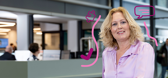 Persoon staat bij een balie in een ruime, moderne centrale hal.