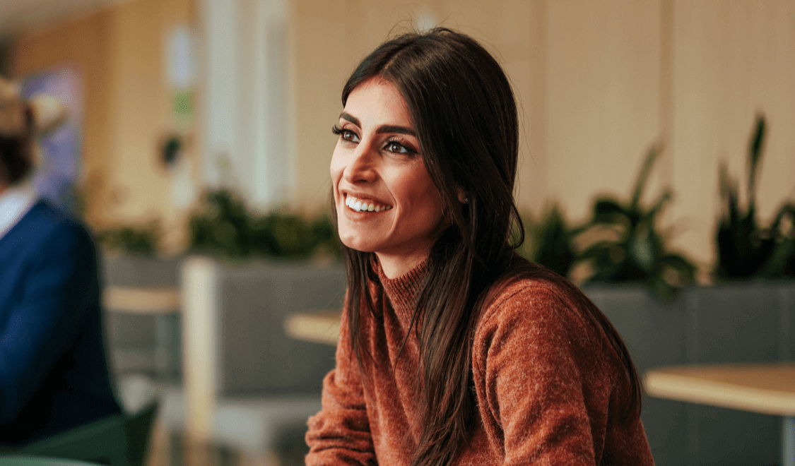 Woman in brown jumper smiling at colleague