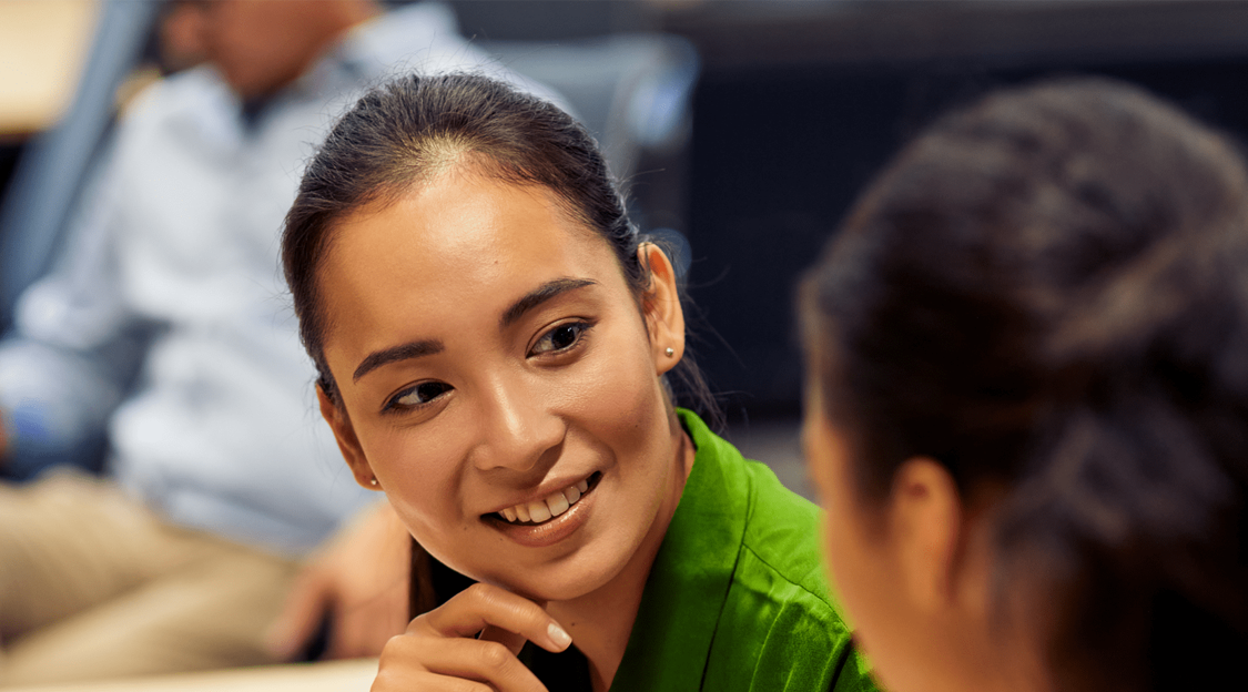 Two colleagues engaged in a conversation in an office environment.