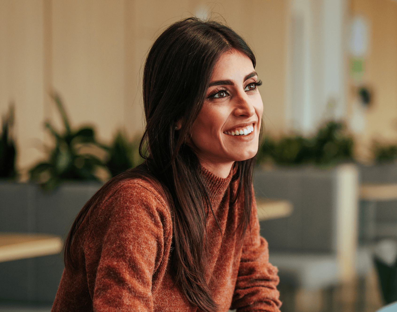 A professional smiling while seated in an office environment.