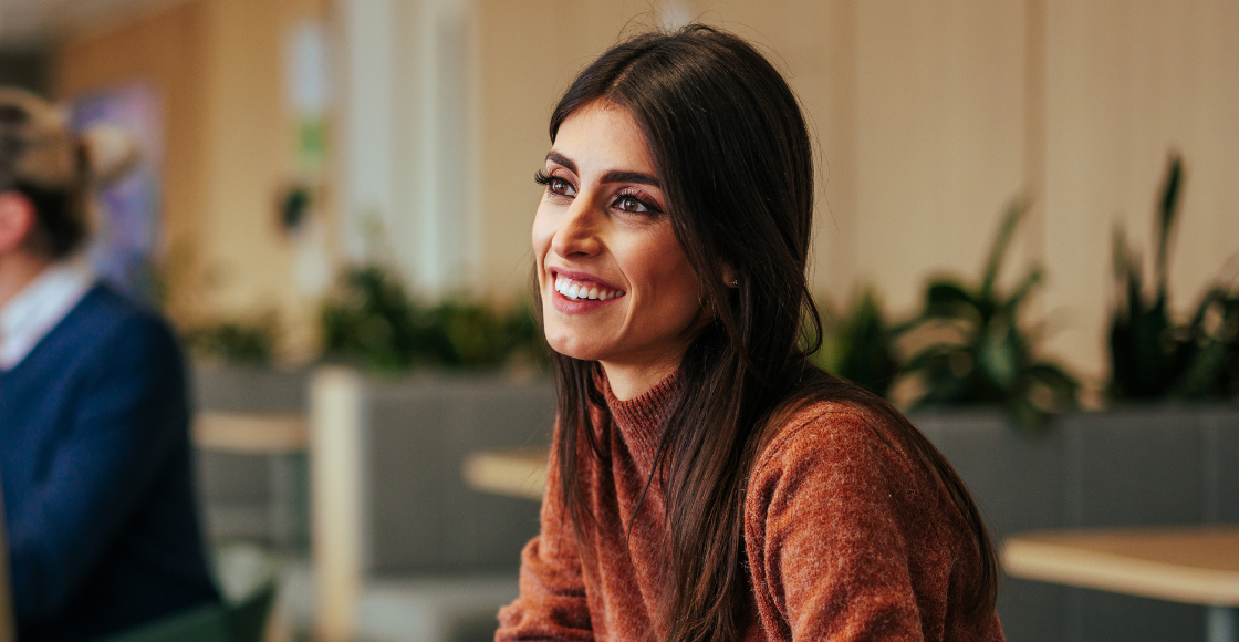 Woman in brown jumper smiling at colleague