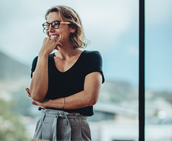 A professional smiling while stood in an office environment.