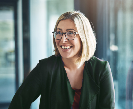 A professional smiling while seated in an office environment.